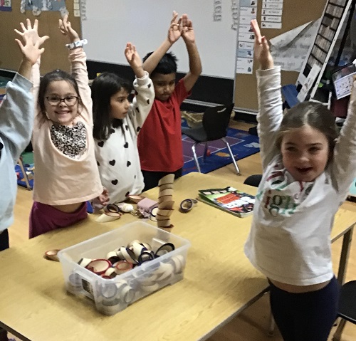 children standing around a table with their hands up in the air
