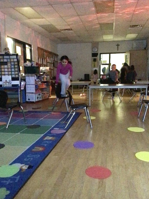 child standing on a chair trying not to touch the floor