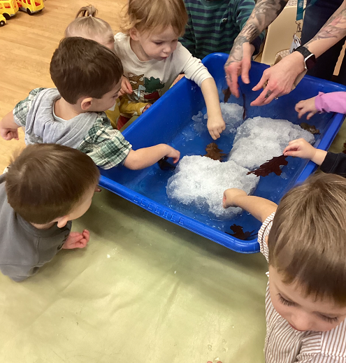 children exploring snow in a bin inside