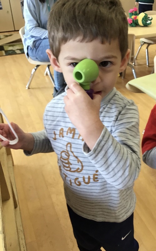 child looking through an otoscope.