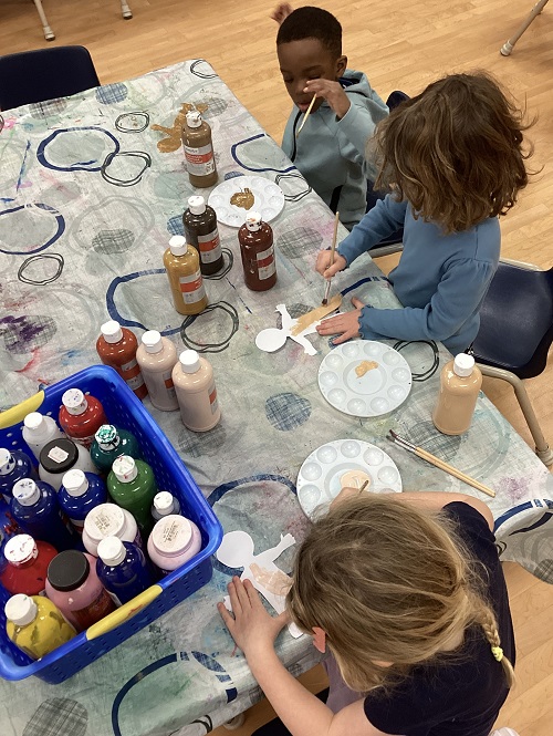 children sitting at a table with different colours of paint