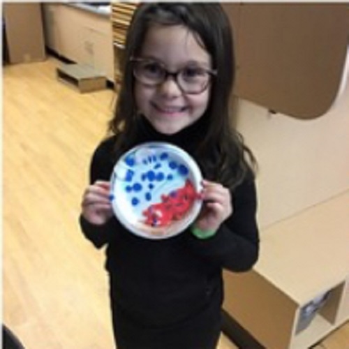 child holding up a craft made from a plate