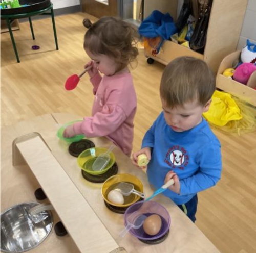 2 children making pretend food items in a classroom