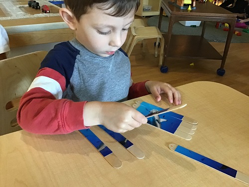child making a popsicle stick whale craft