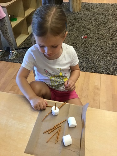 child making a structure with marshmallows and pretzels
