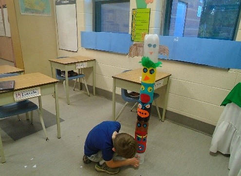 child looking at the totem pole the group create out of plastic bottles