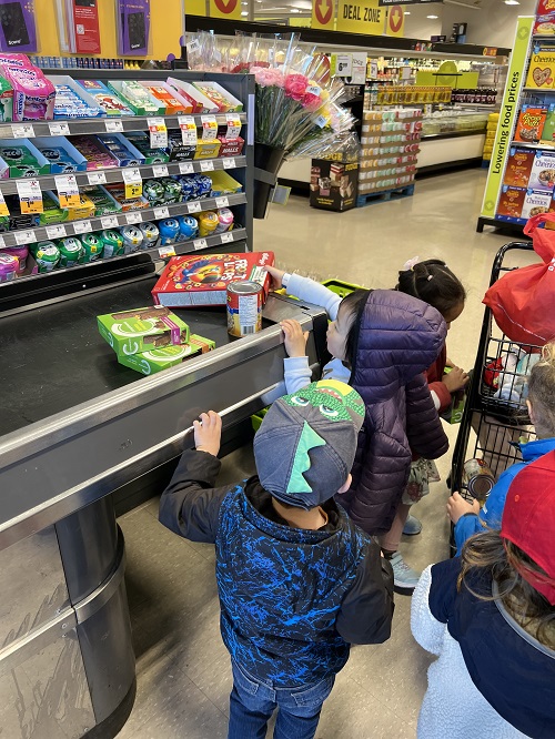 children at the check out putting items onto belt