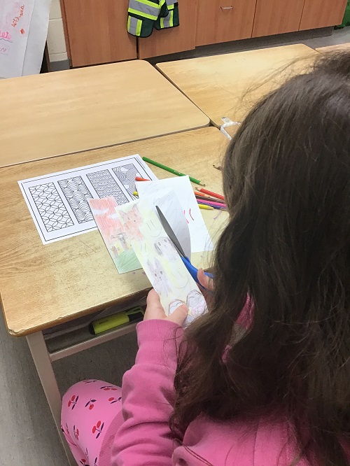child cutting out their bookmark using scissors