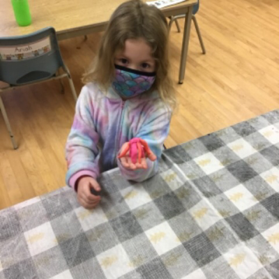 girl showing her spider creation made of playdough