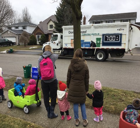 children and educators watcing the recycle truck across the street