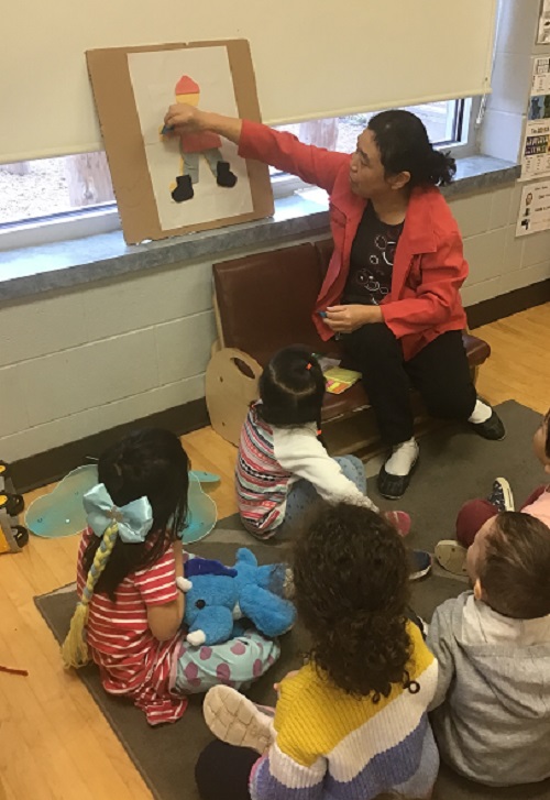 Educator teaching a group of children a song to support dressing for outside. 
