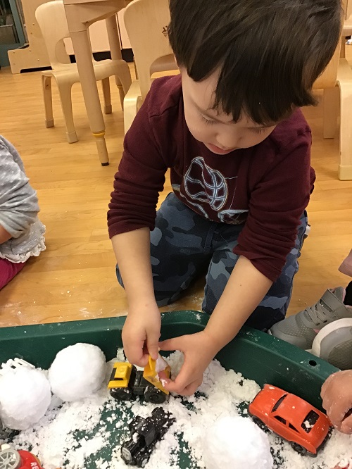 Child dumping fake snow form a small dump truck. 