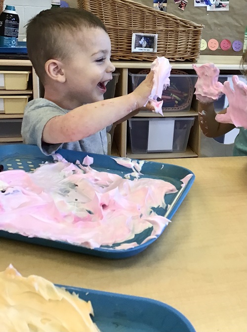 Preschool child exploring shaving cream with hands