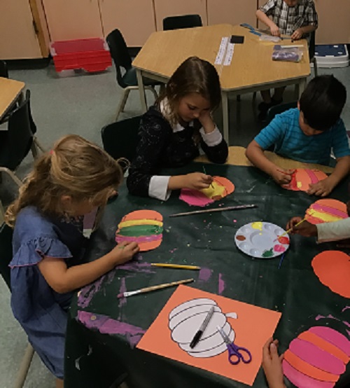 Children creating paper pumpkins. 