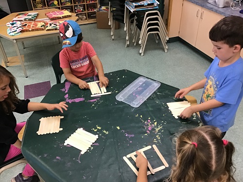 Children gluing and taping popsicle sticks.