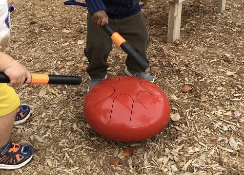 Toddler children making sounds on the metal drums
