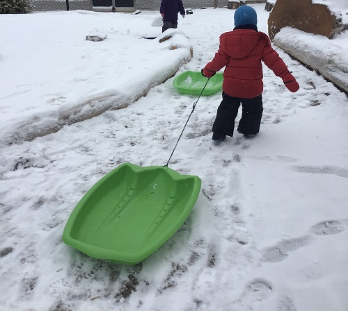 Child pulling a sled outdoors. 