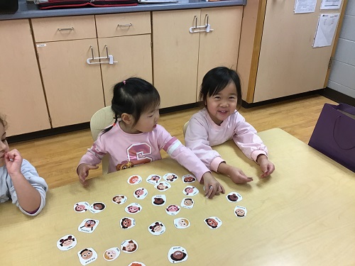 Two children playing an emotions match game.