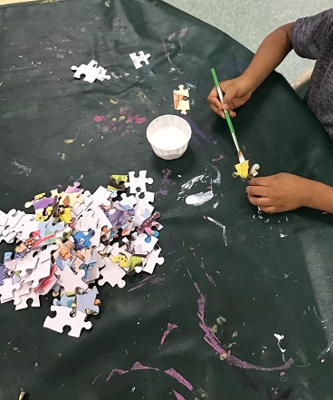 Child painting an old  puzzle piece.