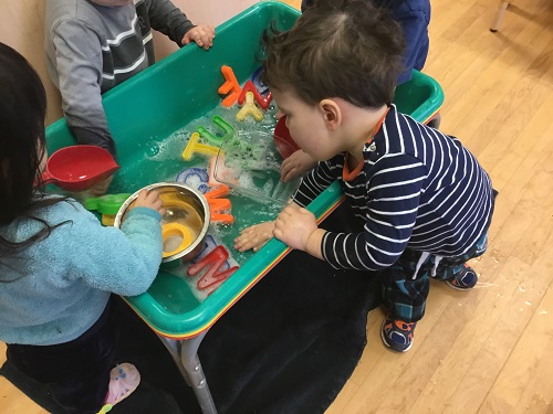 Children exploring water play in the sensory bin. 