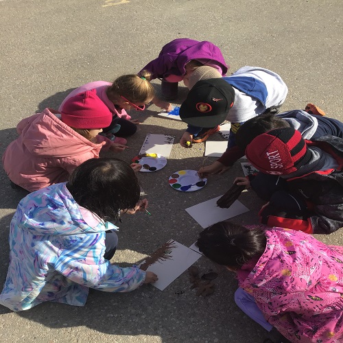 Group of children painting together with natural materials. 