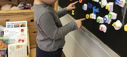 Child pointing to letters.