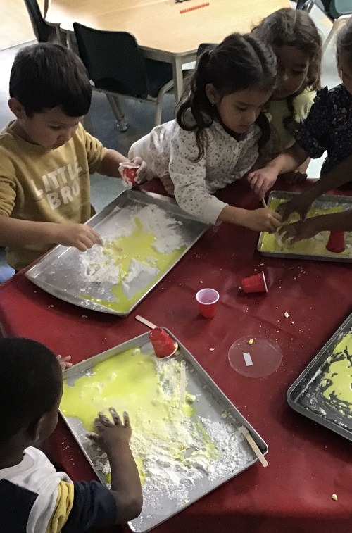 Group of children mixing corn starch and coloured water.