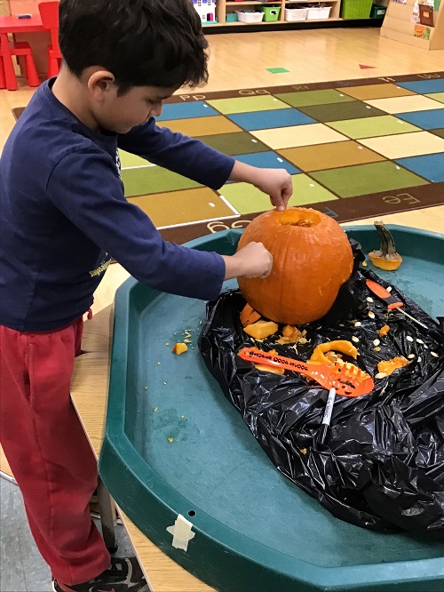 Child carving part of the pumpkin.