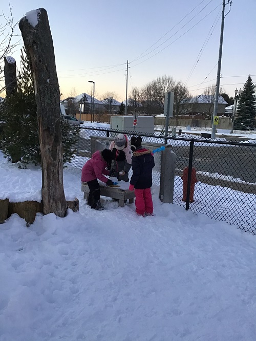 Children pretending to cook with snow.