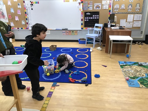 Child taking their turn to toss ball towards the buckets.