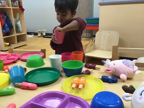 CHild pretending to mix something in a cup.