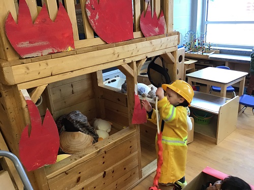 Child pretending to put out a fire with the hose.