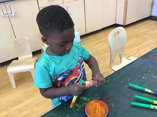 Child opening paint to use on their flower pot.