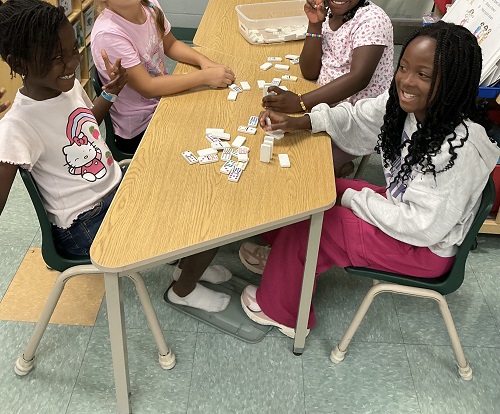 Group of children playing with dominos and laughing together.