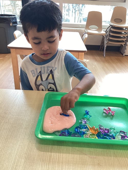 A toddler child pushing gems into slime