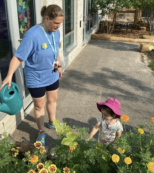 An infant and an educator working on the garden