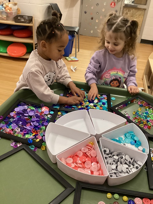 2 preschool children engaged in play using a variety of loose parts at a tuff tray