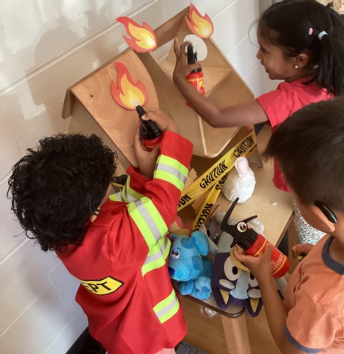 Preschool children putting out a pretend fire on some blocks