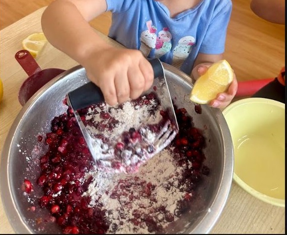A preschool child mashing up the service berries