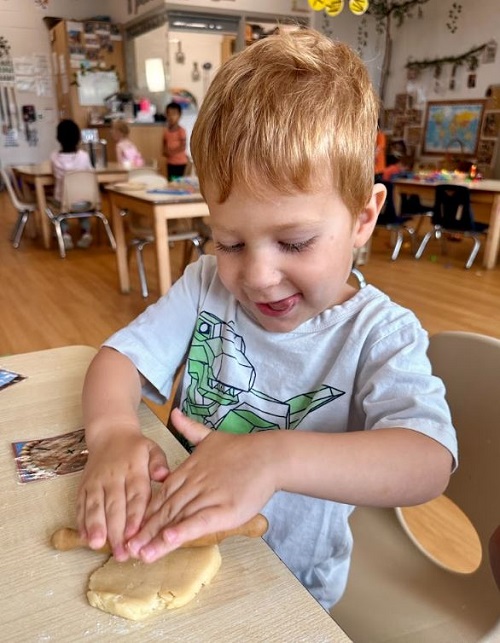 A preschool child making pie dough