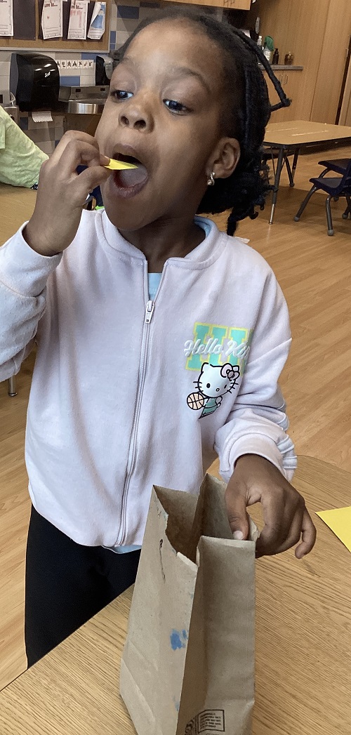 A school age child pretending to eat the chips she made