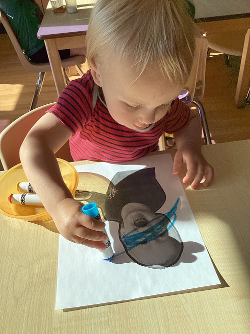 A toddler child colouring their photo