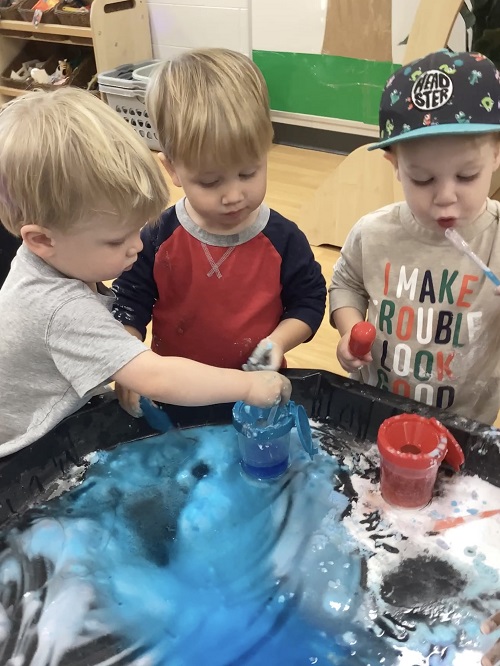 A group of toddlers exploring baking soda and vinegar mixtures