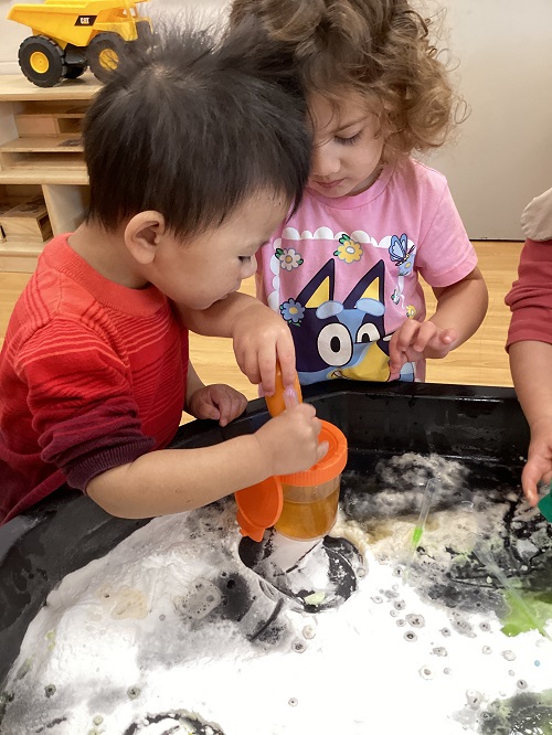A group of toddlers exploring baking soda and vinegar mixtures