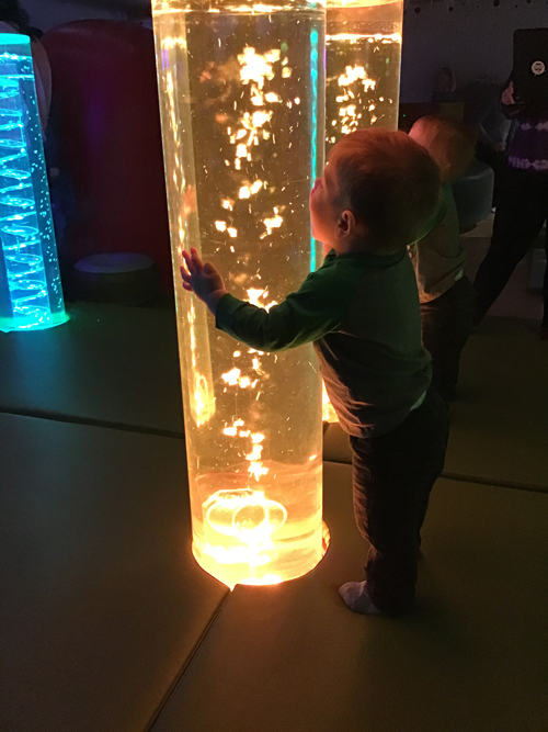 child looking at a tube full of water that is lit up