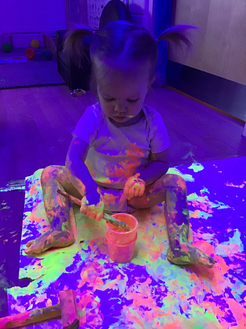 child getting messy painting on the floor