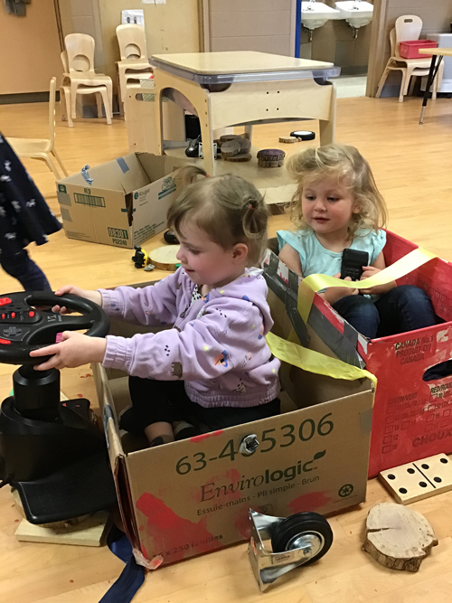 kids sitting in their cardboard made car