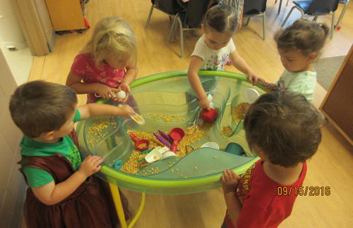 children playing with popcorn seeds in a bin