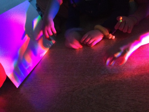 Children shinging colourful lights on white paper