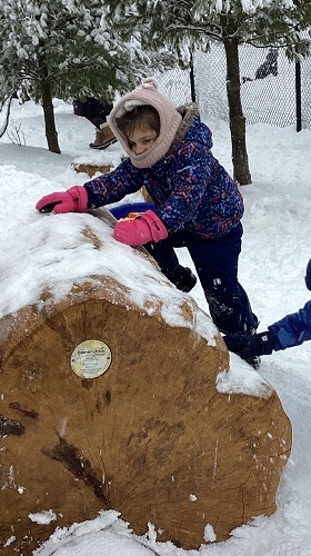 A child climbing up a pile of snow to slide down the other side